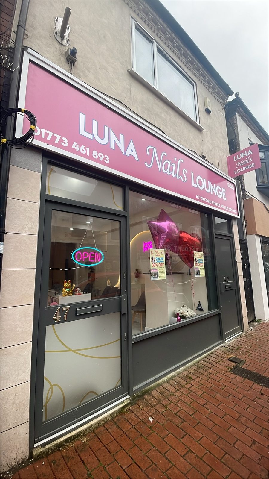 The shopfront: pink Luna Nails Lounge sign over a grey frontage on Oxford Street